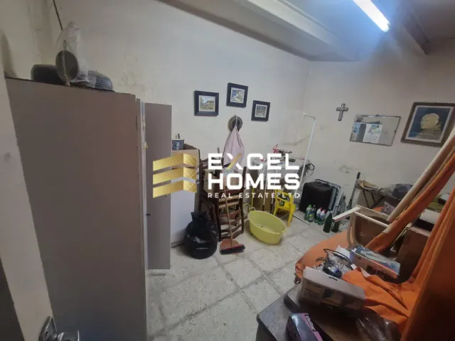 a room with a refrigerator, a bed, and a trash can