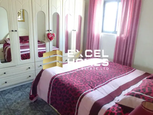 a bedroom with a bed, dresser, and a lamp