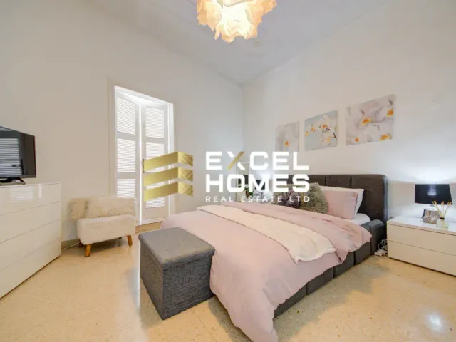 a bedroom with a bed, desk, and television 