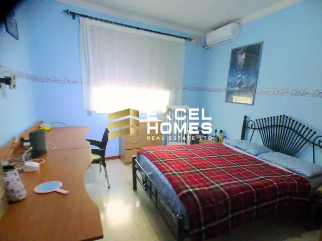 a bedroom with a bed, desk, and a laptop 