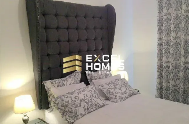 a bed with a white comforter and a black pillow