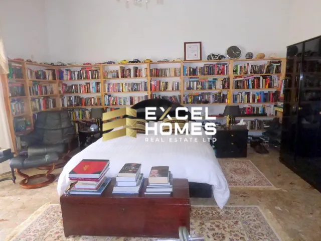 a living room with a bed, bookshelf, and a television 