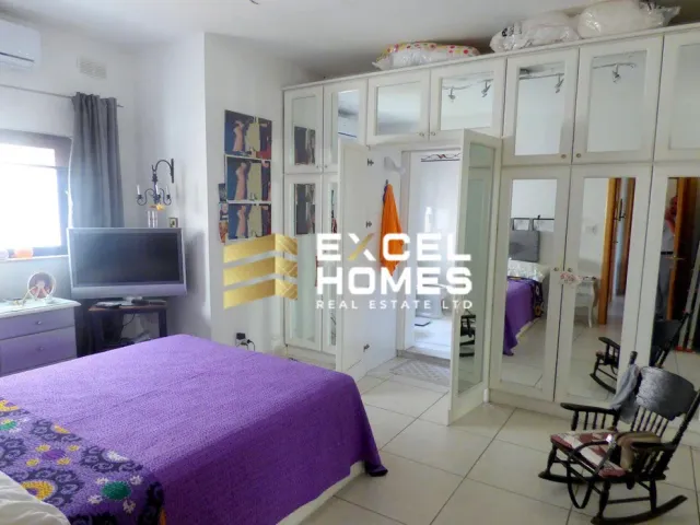 a bedroom with a bed, chair, and a television