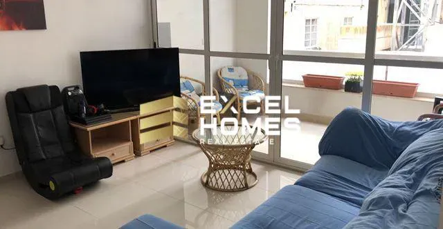 a living room with a couch, chair, tv and a window