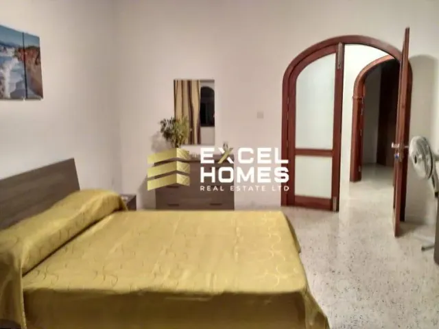 a bedroom with a bed, chair, and a tv