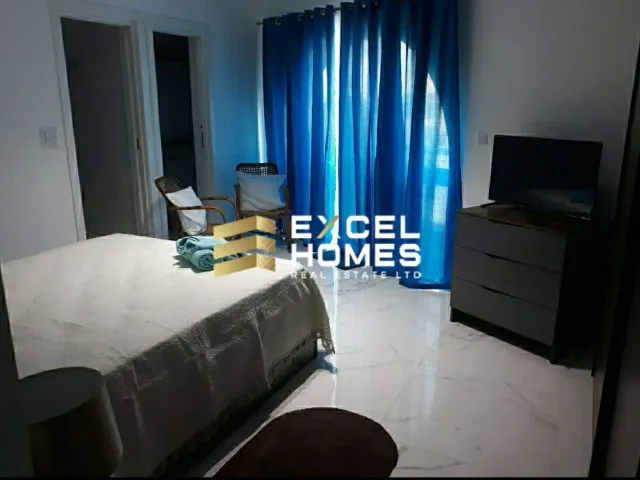 a bedroom with a bed, desk, and television