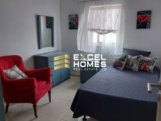 a bedroom with a bed, chair, and a lamp