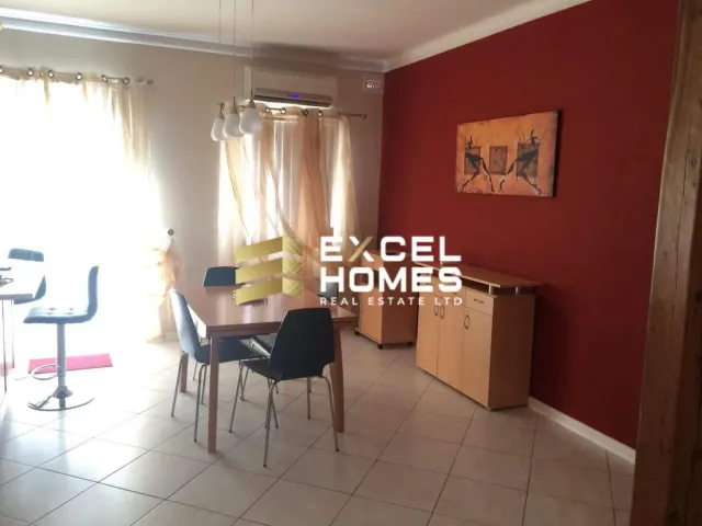 a room with a table, chairs, and a refrigerator