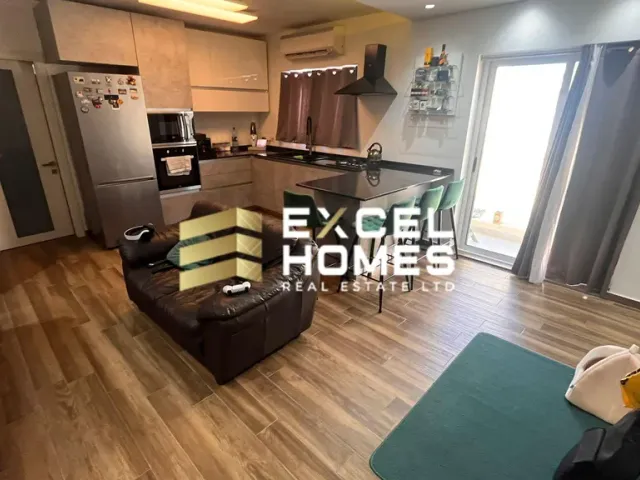 a living room with a couch, coffee table and a refrigerator