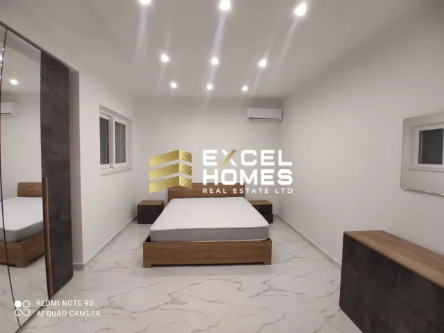 a bedroom with a bed, desk, and a lamp