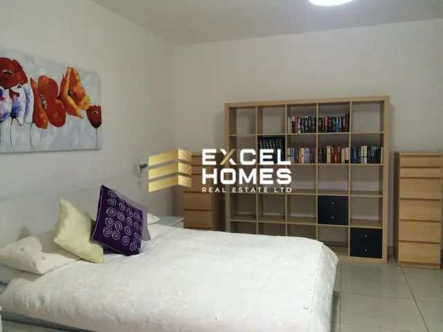 a bedroom with a bed, a desk, and a painting on the wall