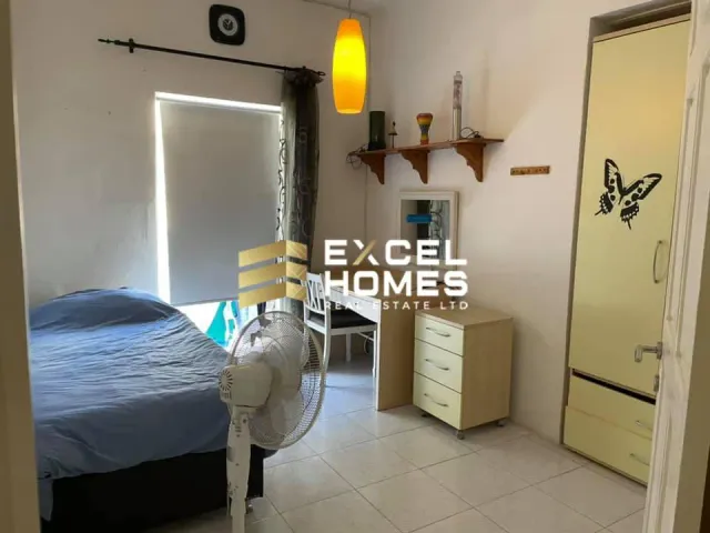 a bedroom with a bed, desk, and a lamp 
