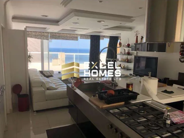 a kitchen with a stove, sink, and a tv 