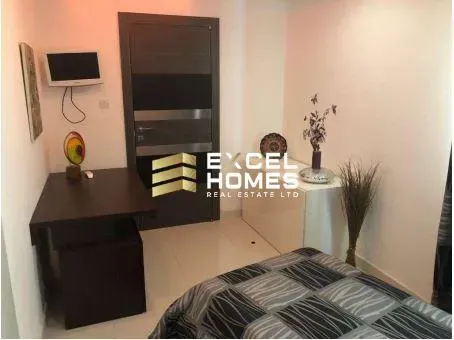 a bedroom with a bed, desk, and television 