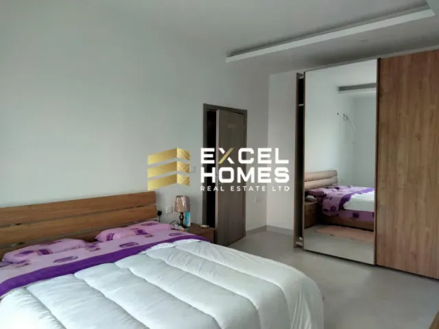 a bedroom with a bed, desk, and a mirror