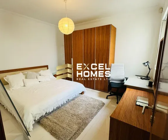 a bedroom with a bed, desk, and a lamp