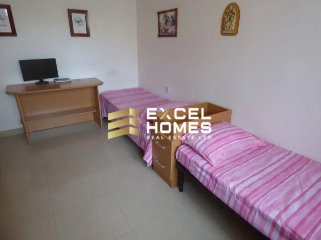 a bedroom with a bed, desk, and a television