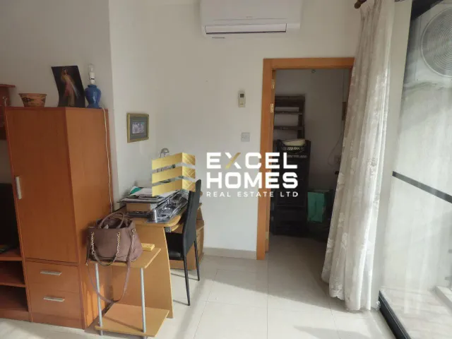 a room with a refrigerator, a desk and a chair