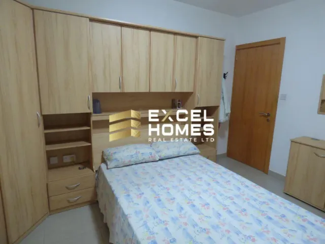 a bedroom with a bed, a dresser, and a refrigerator