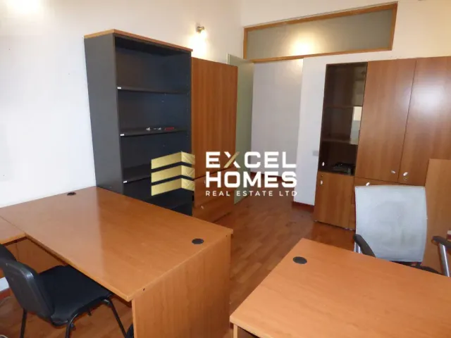 a room with a desk, chair, and a television
