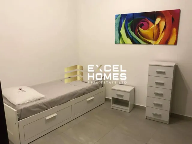 a bedroom with a bed, desk, and a painting