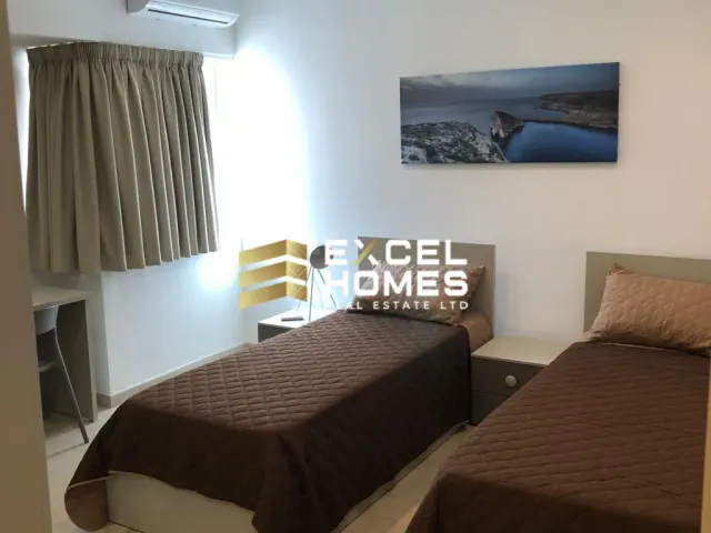 a bedroom with a bed, desk, and a painting on the wall 