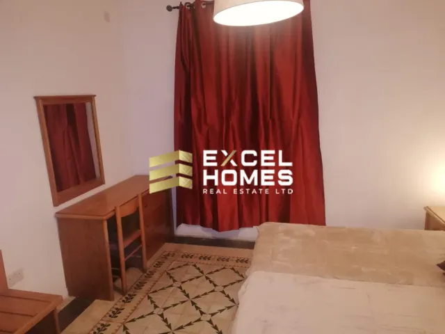 a room with a bed, a table and a lamp 