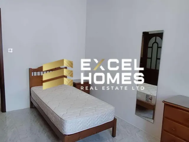 a bedroom with a bed, desk, and a lamp