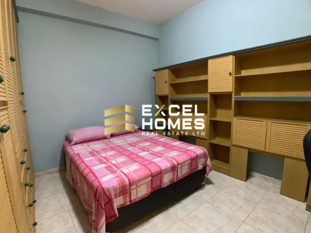 a bedroom with a bed, desk, and a bedspread