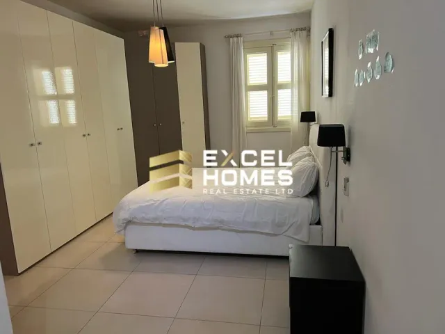 a bed room with a white bedspread and a white wall 
