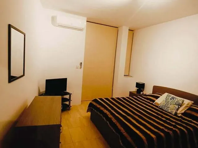 a bedroom with a bed, desk, and a television 