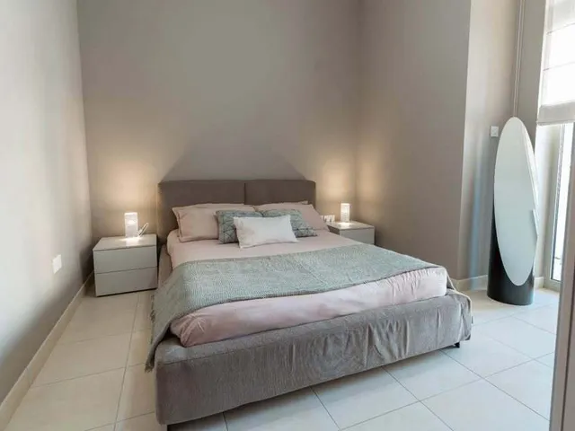 a bed room with a white bedspread and a white wall 