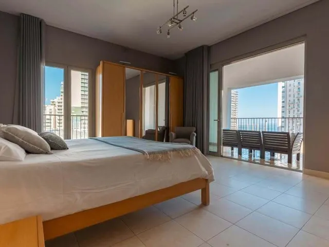 a bedroom with a bed, chair, and a window 
