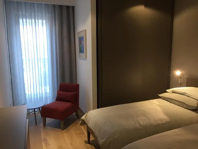 a bedroom with a bed, chair, and a lamp