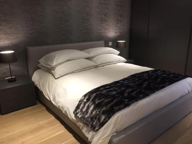 a bed with a white comforter and pillows