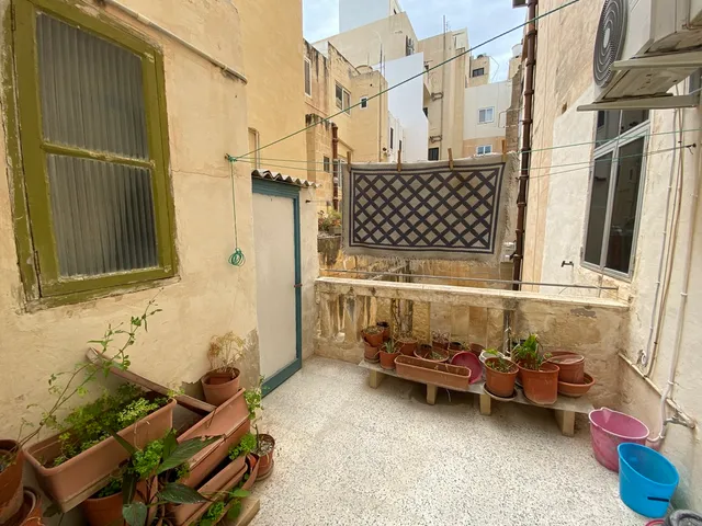 a small garden with a wooden bench and a window 