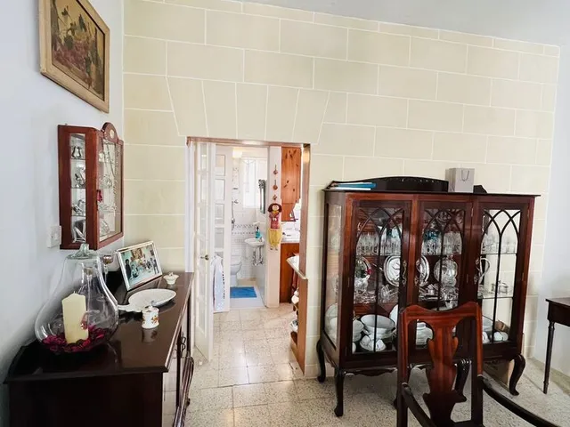 a room with a table, chairs, and a vase on the wall