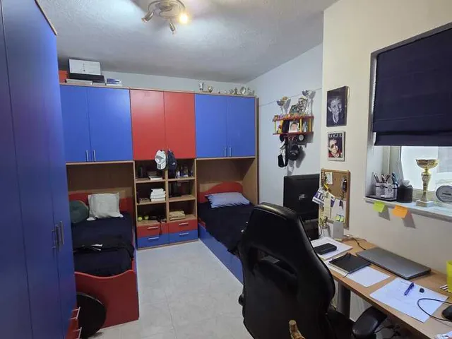 a room with a desk, chair, and a television