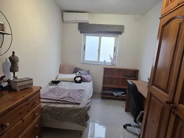 a bedroom with a bed, desk, and a window