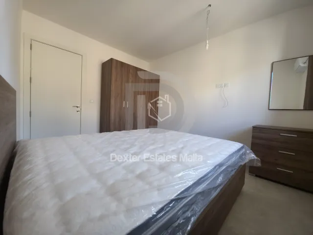 a bedroom with a bed, dresser, and a mirror