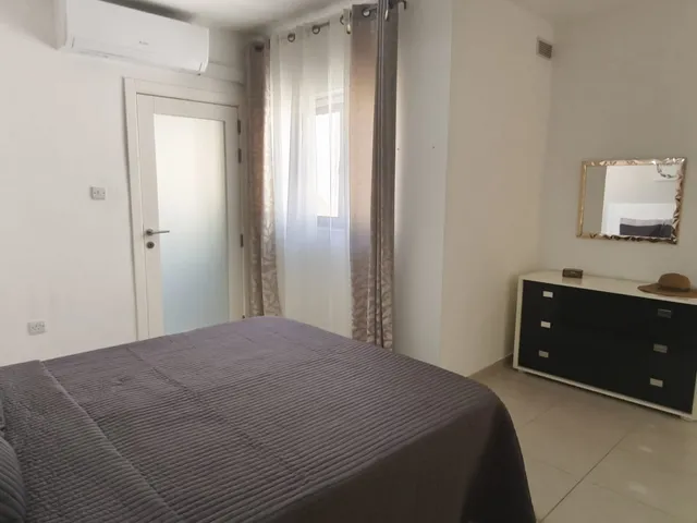 a bedroom with a bed, a dresser and a television