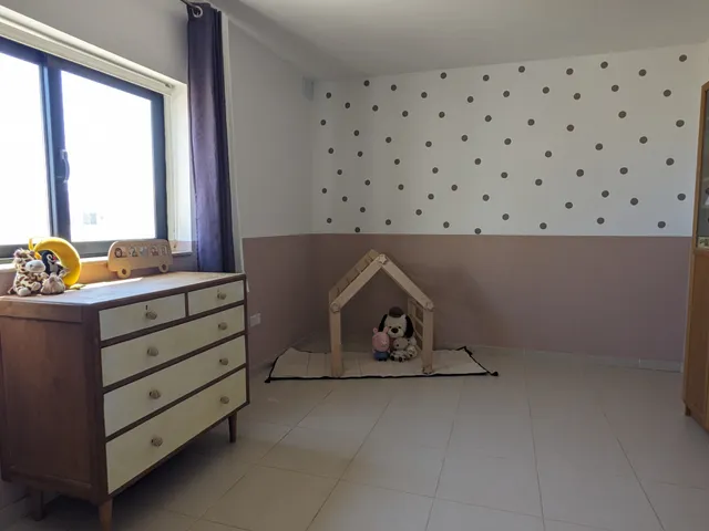 a room with a bed, a dresser, and a window