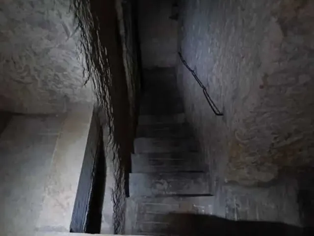 a small tunnel with a stone wall and a stone staircase