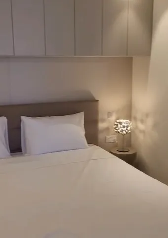 a white bed with a white comforter and a lamp